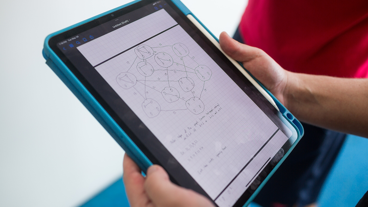 A close-up of a computer tablet in a blue case being held by two hands.